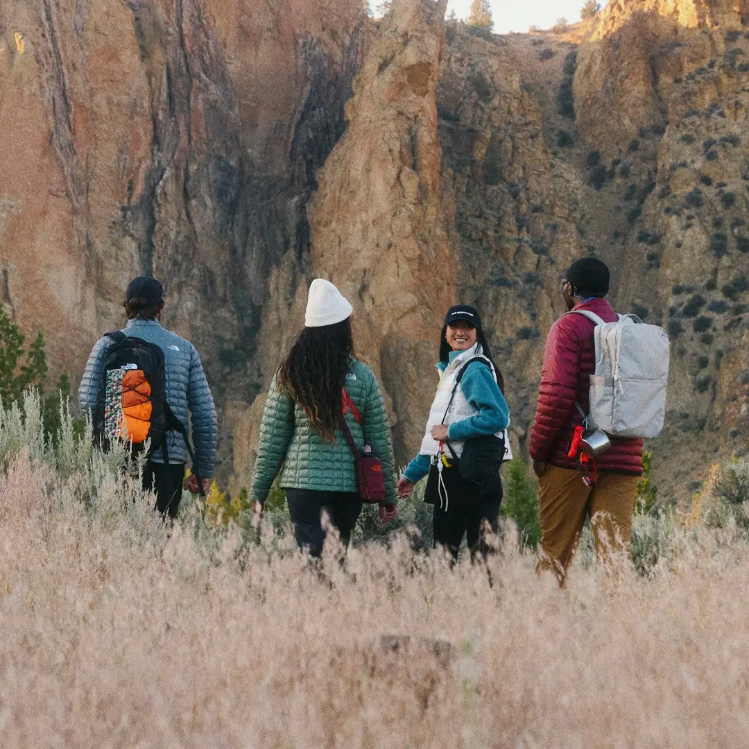 Grupo caminhando em trilha com paredões de pedra ao fundo
